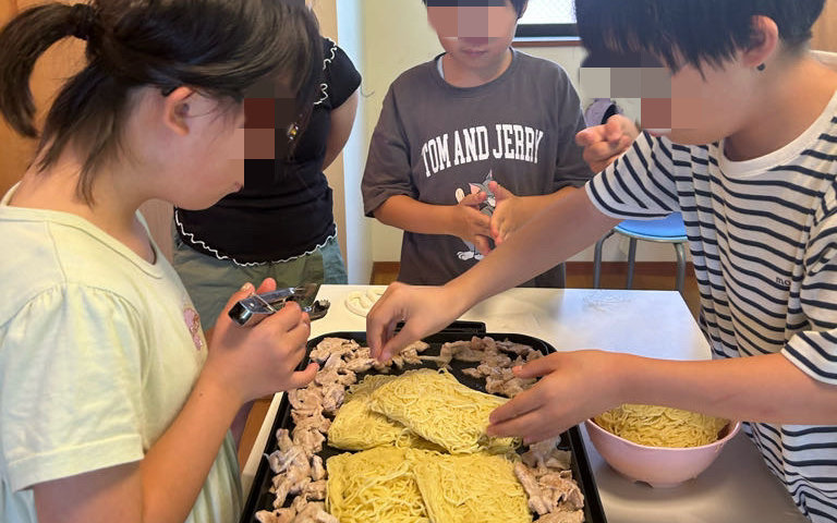 ホットプレートで一緒に焼きそばを作る子どもたち